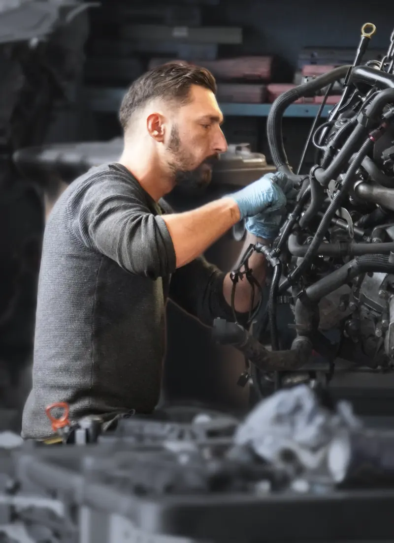 Mechaniker mit Handschuhen an einem ausgebauten Motor